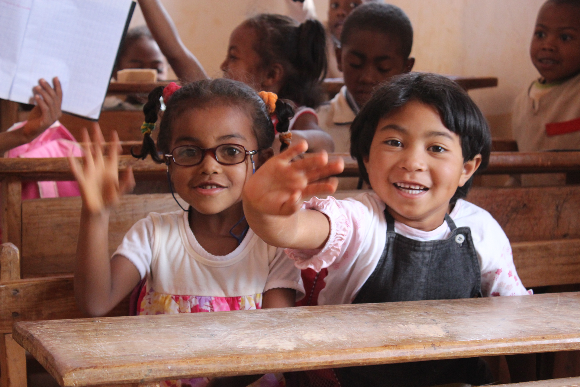 Two young children smiling at the classroom desks at the Ambondrona School, Madagascar