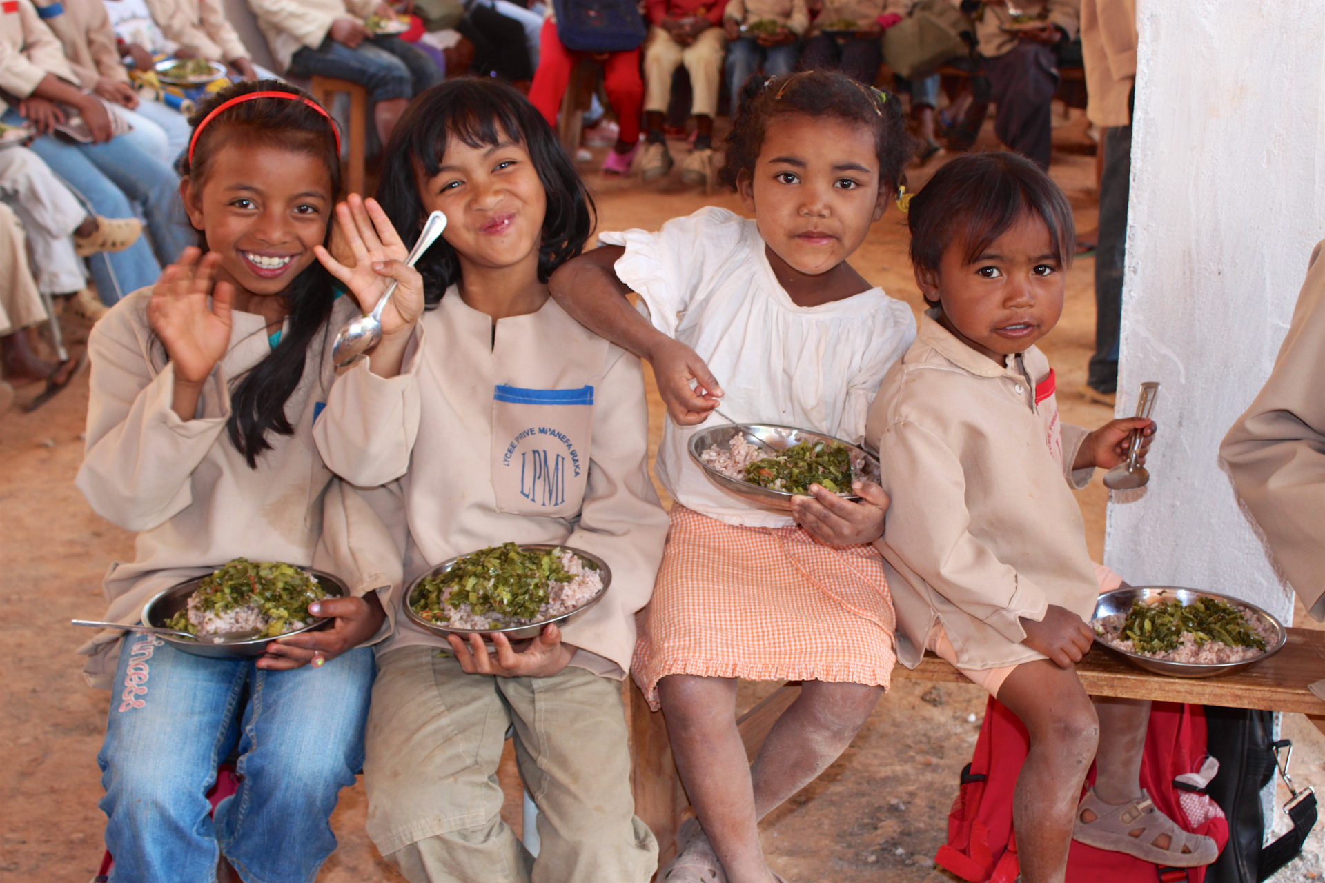 Group of four young girls smiling and eating at the Ambondrona School, Madagascar