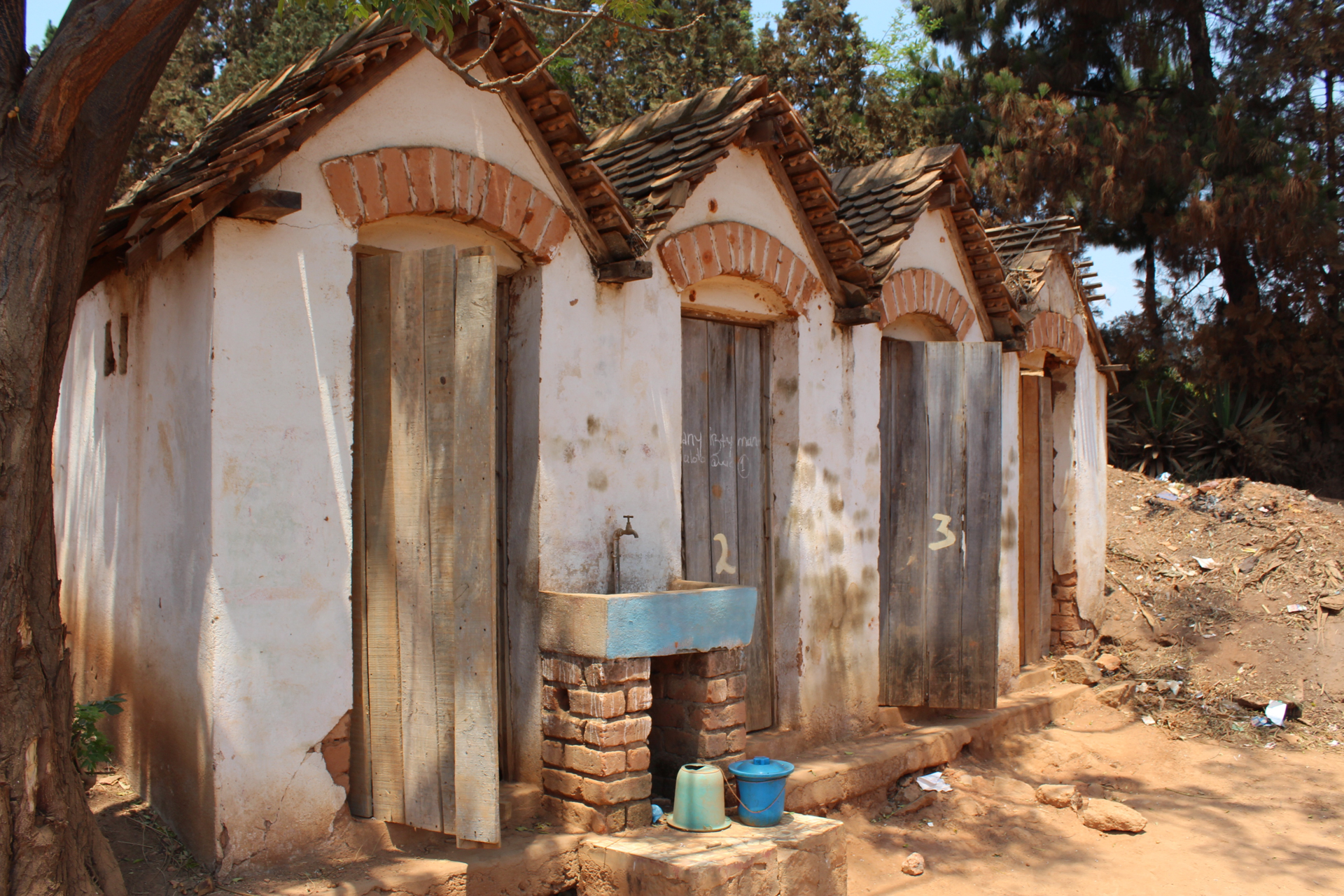 Group of four outside huts with a tap of running tap water in Le Triomphe's Children's orphanage in Madagascar