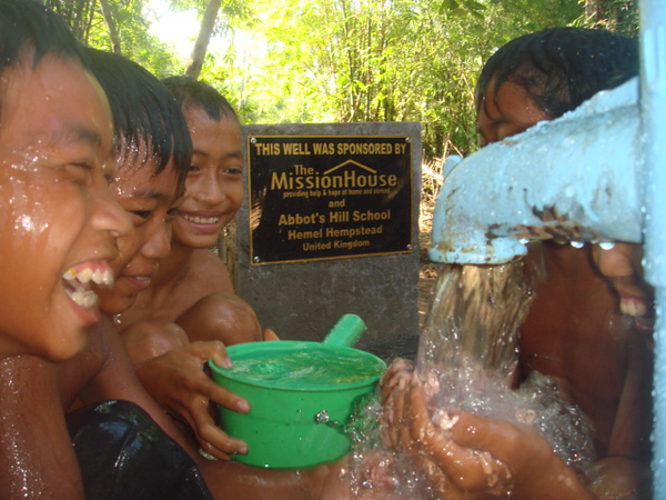 Children smiling and laughing over a water tap in the Ambondrona School, Madagascar